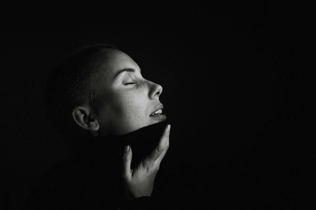 Intimate black and white portrait of a woman with closed eyes and serene expression.